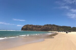 A beach with a sandy shore, a rocky hill in the background, and a clear blue sky. - Relax and unwind at Pacific Blue - 500m to Orchid Beach (Orchid Beach, Fraser Island)