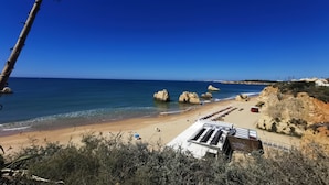 A beach with clear blue water, rocky outcrops, and a few people.