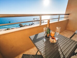 Ein Balkon mit Tisch für zwei Personen, ausgestattet mit einer Champagnerflasche, zwei Gläsern und einem Kerzenständer.