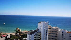 A coastal view with a building in the foreground and a rocky outcrop in the water.