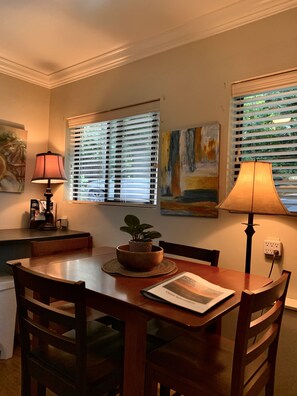 A dining area with a wooden table, chairs, a potted plant, and two lamps. - The Fraser River's Edge B&B Lodge (Chilliwack)