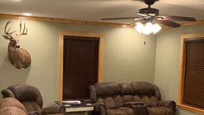 A room with a ceiling fan, a mounted deer head, and two reclining leather sofas.