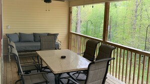 A covered patio with a table and chairs, a sofa, and a ceiling fan.