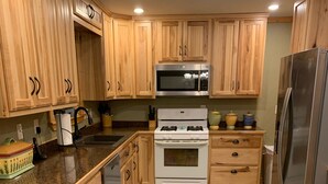 A kitchen with wooden cabinets, a stove, a microwave, and a refrigerator.
