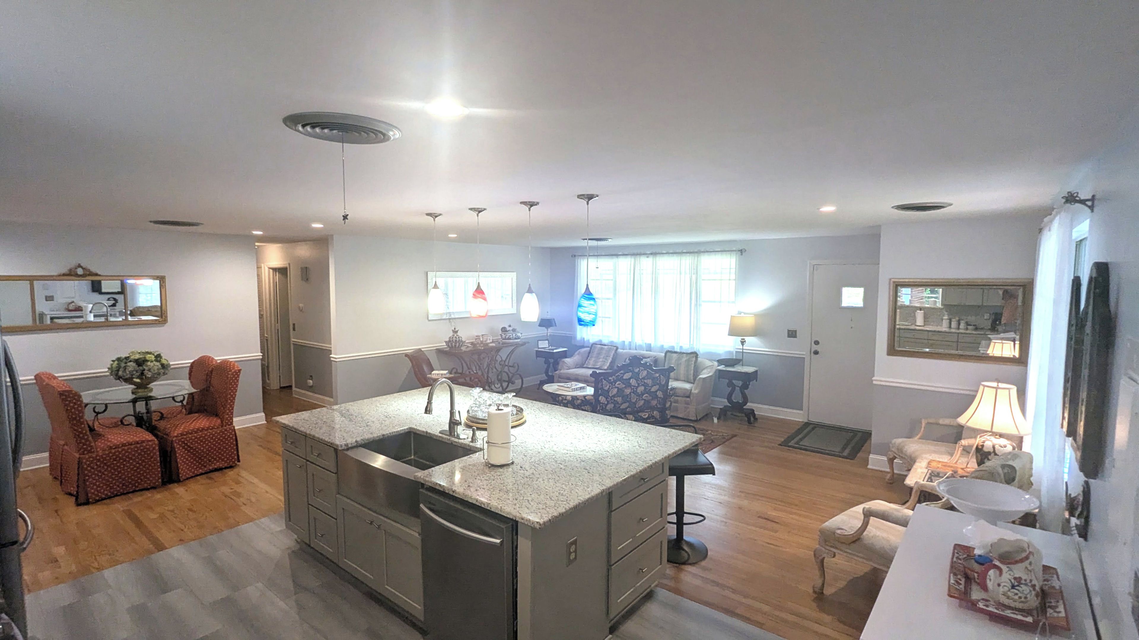 A spacious kitchen with a central island, a dining area with a round table, and a living room with a sofa and a coffee table.