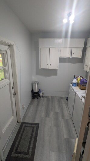 Een kleine keuken met witte kastjes, een roestvrijstalen spoelbak en een klein aanrecht.