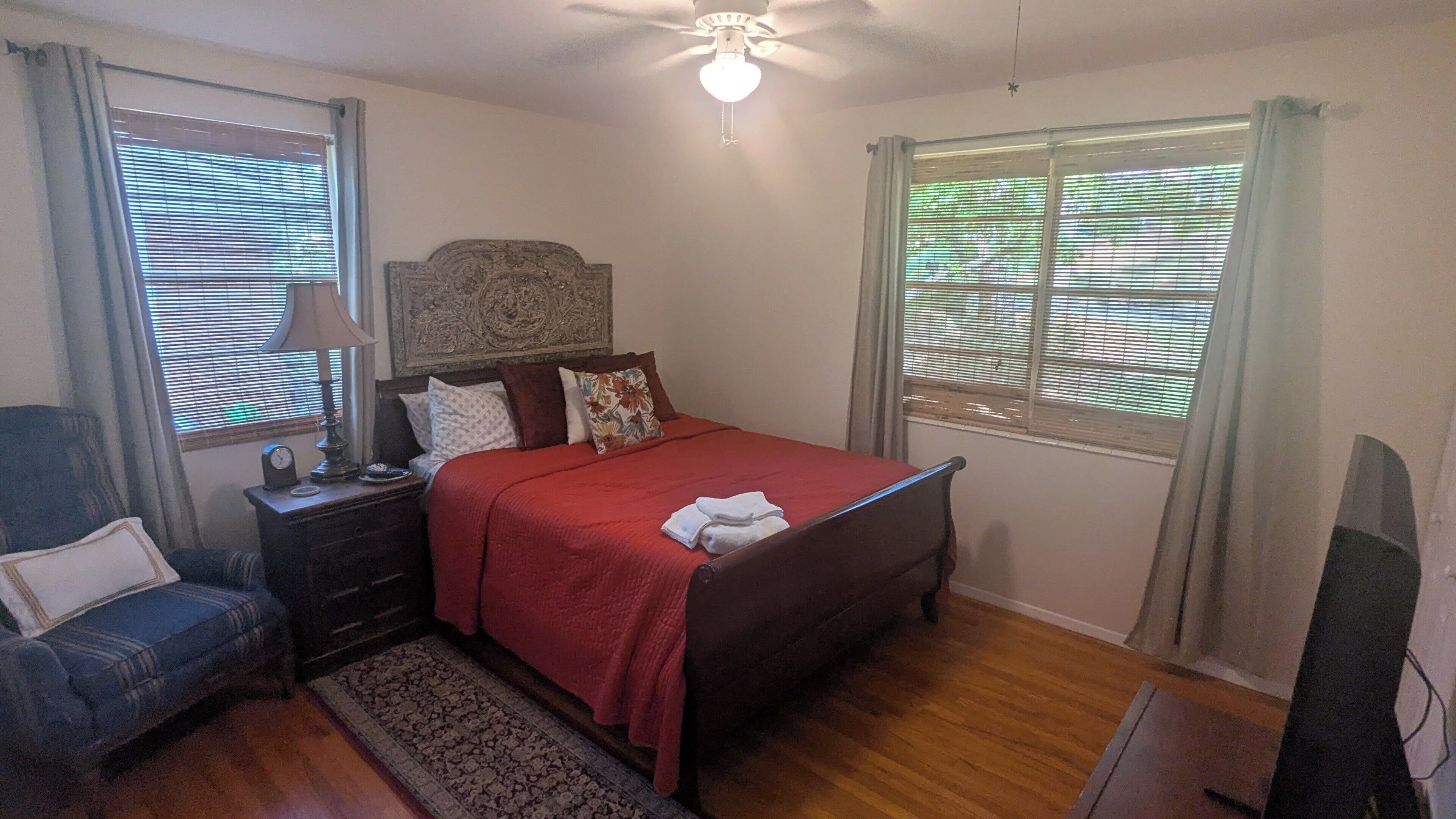 A bedroom with a bed, nightstand, lamp, and a ceiling fan.