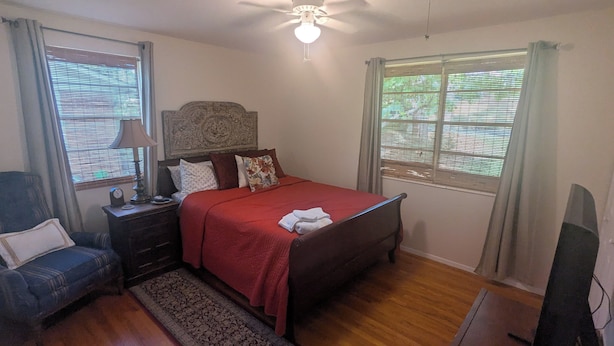 Une chambre à coucher avec un lit, une table de chevet, une lampe et un ventilateur de plafond.
