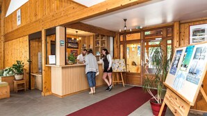 A wooden interior with a reception desk, a red carpet, and informational posters.