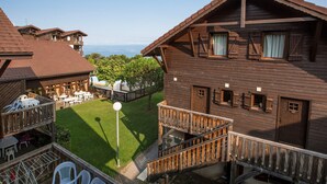A wooden cabin with a balcony, a lawn, and a view of the sea.