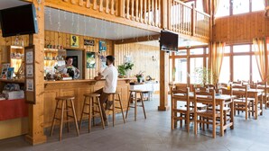 A wooden interior with a bar area, multiple tables, and chairs.