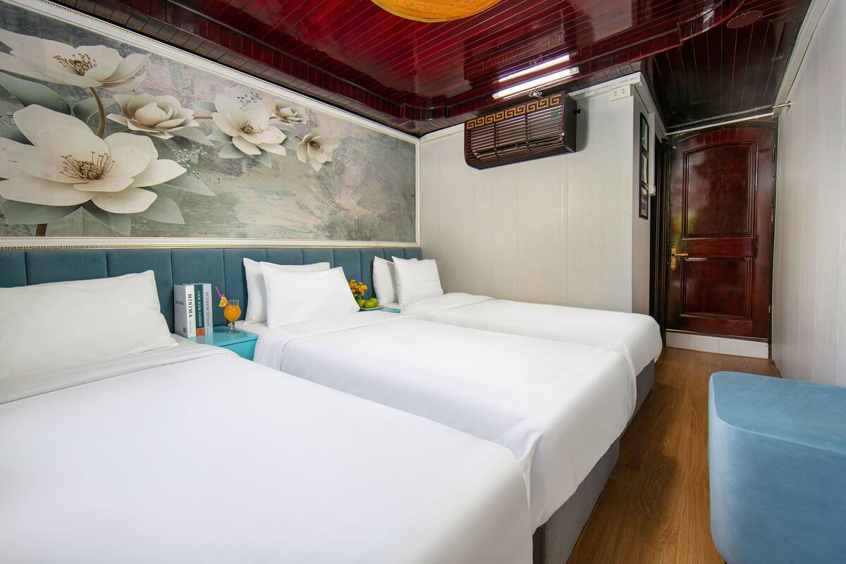 A hotel room with two beds, a large floral mural on the wall, a blue accent wall, and a wooden door.