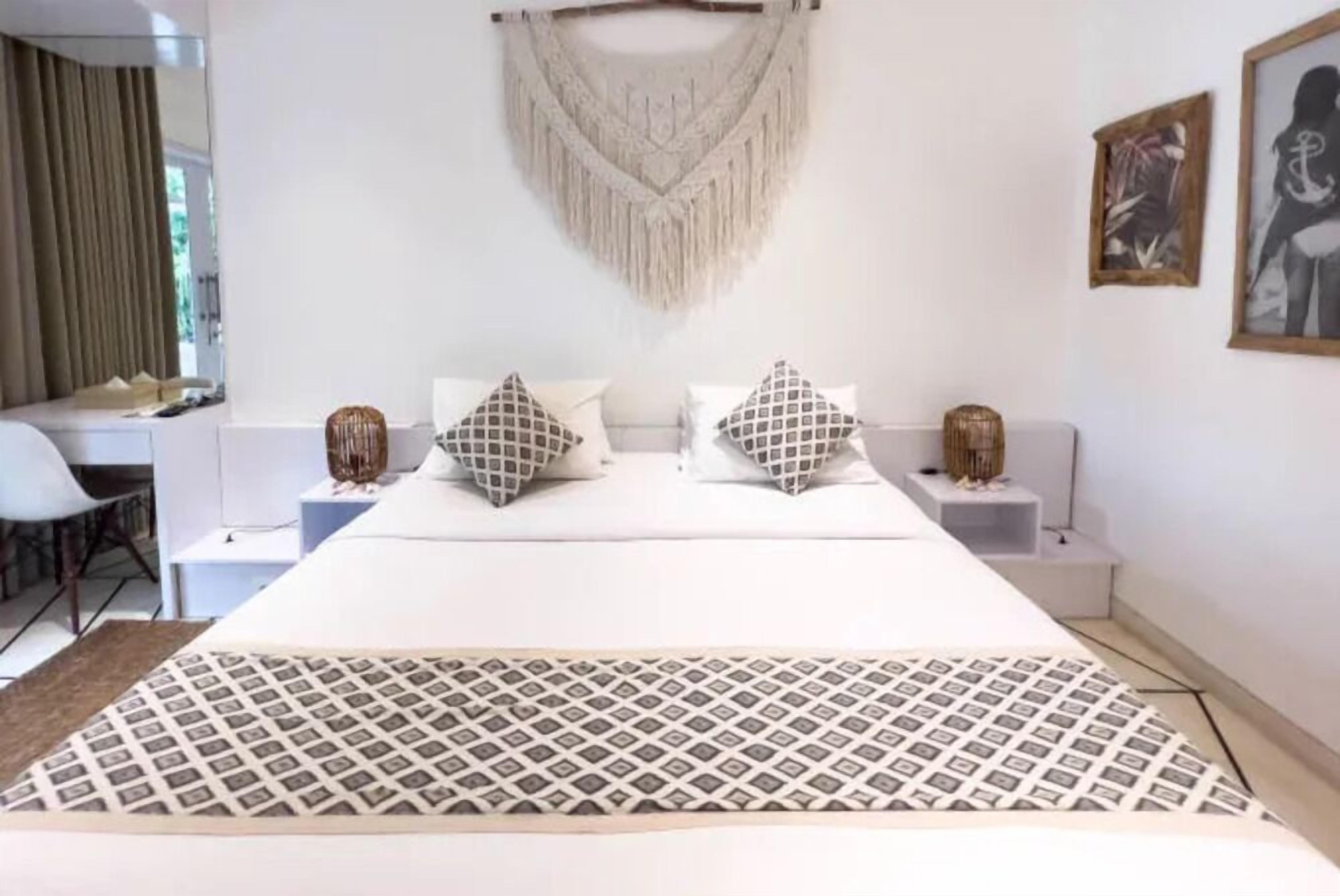 Una habitación de hotel con una cama grande, dos mesitas de noche, un escritorio y una silla.