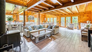 A spacious log cabin with a large living area featuring a sofa, coffee table, and a wood stove. - Luxurious & Enchanting Log House in Heart of Hudson Valley/Catskills, Upstate NY (Saugerties)