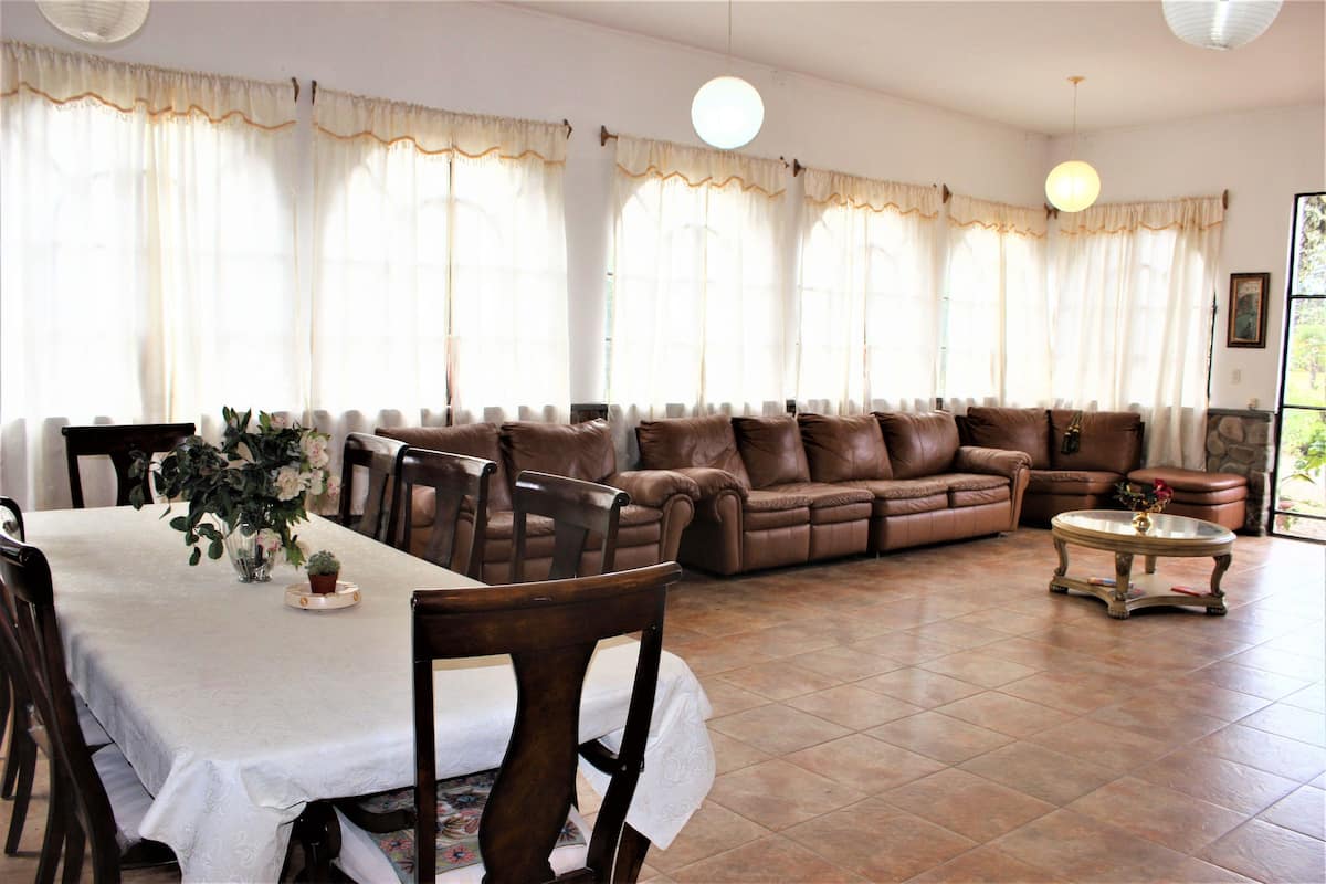A living room with a brown leather sofa, a dining table with chairs, and a coffee table.