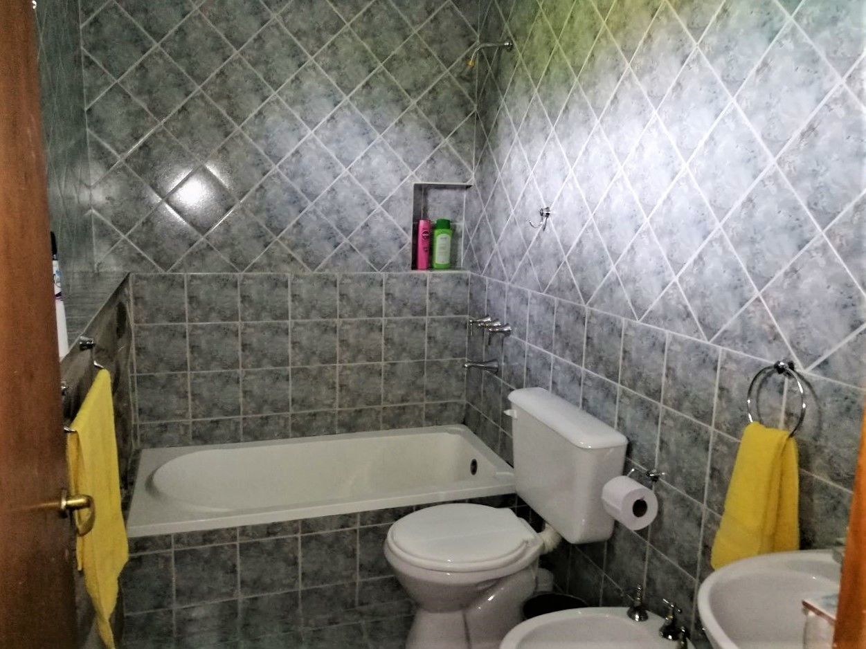 A bathroom with a bathtub, toilet, and sink. There are two yellow towels hanging on hooks.