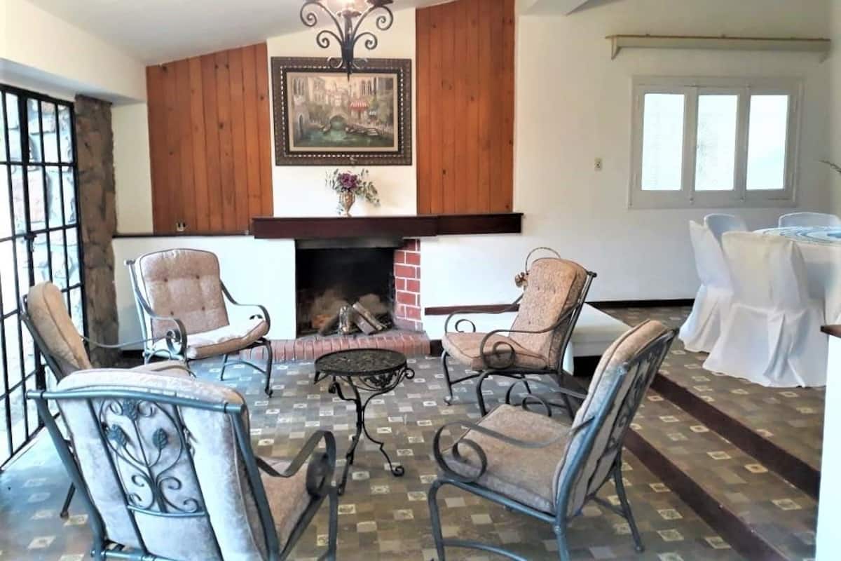A cozy living room with a fireplace, patterned floor, and metal chairs.
