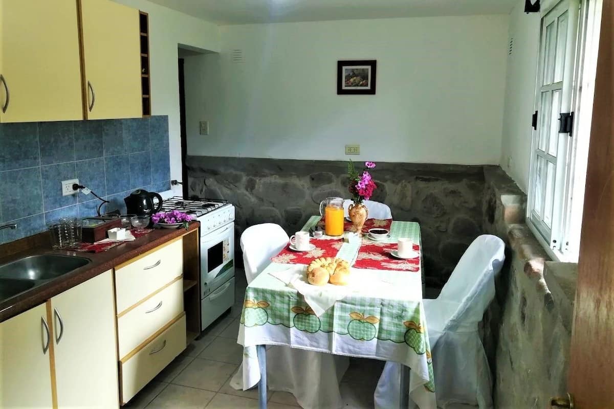 A compact kitchen with a dining area, featuring a table set with breakfast items, a stove, and a sink.