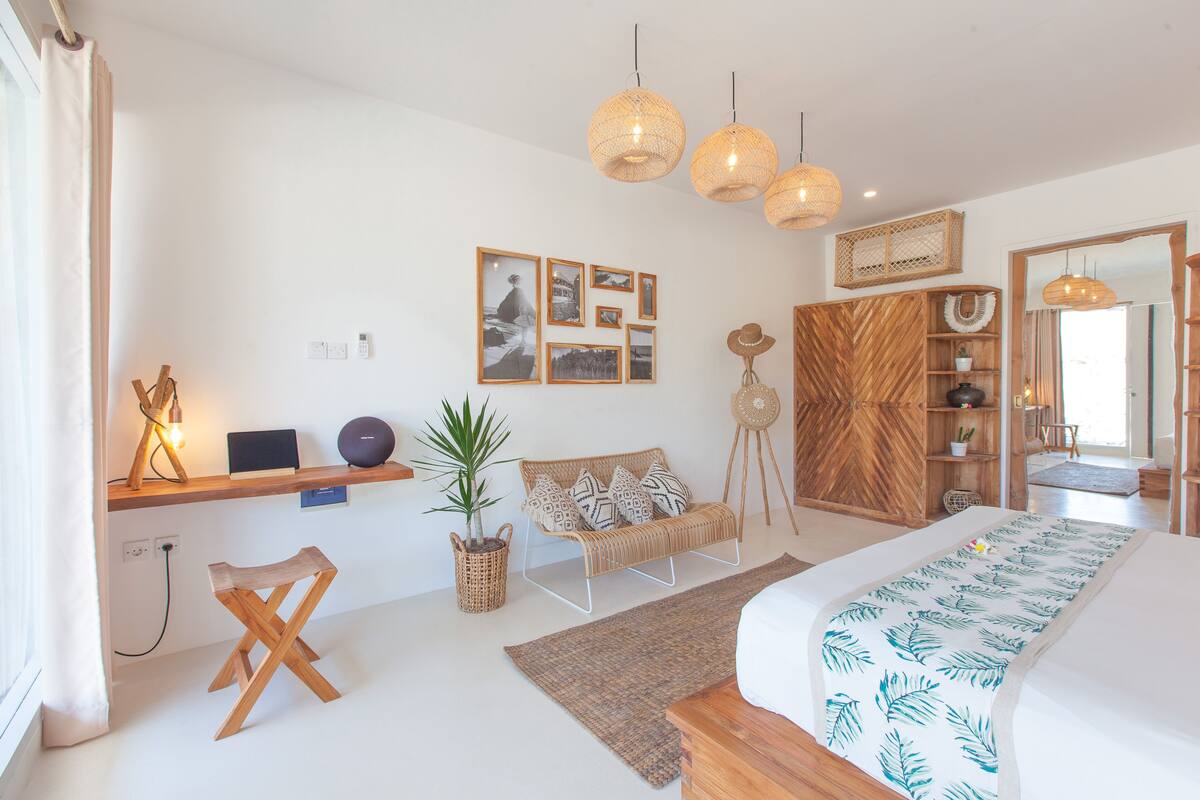 A modern bedroom with a bed, bedside table, lamp, and wall art.