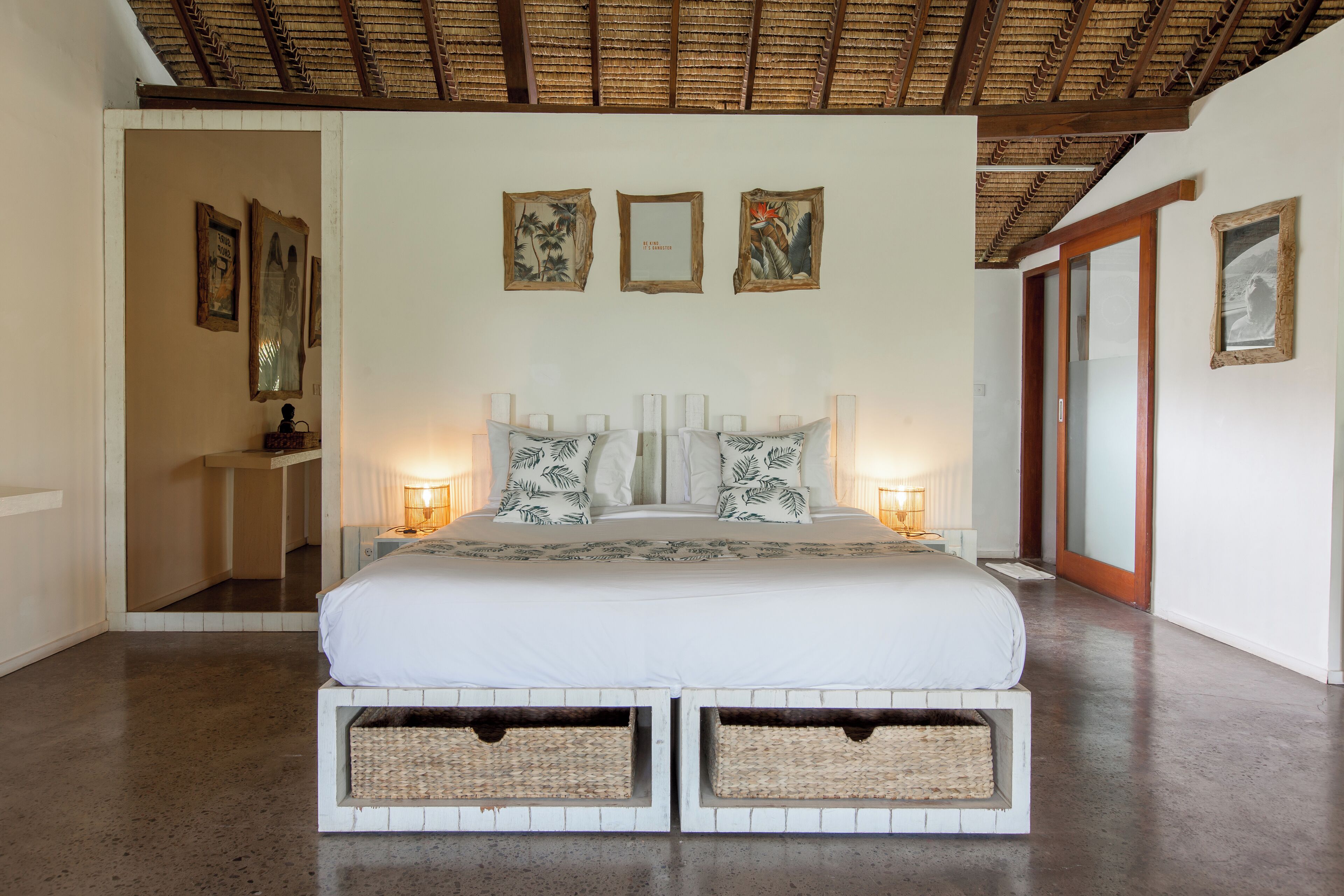 Un dormitorio con una cama grande, mesitas de noche, una obra de arte en la pared y un techo con vigas de madera.