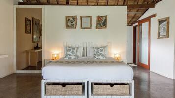 Un dormitorio con una cama grande, mesitas de noche, una obra de arte en la pared y un techo con vigas de madera.