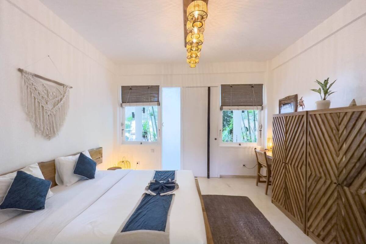 A bedroom with a bed, bedside tables, a desk, and a chair.