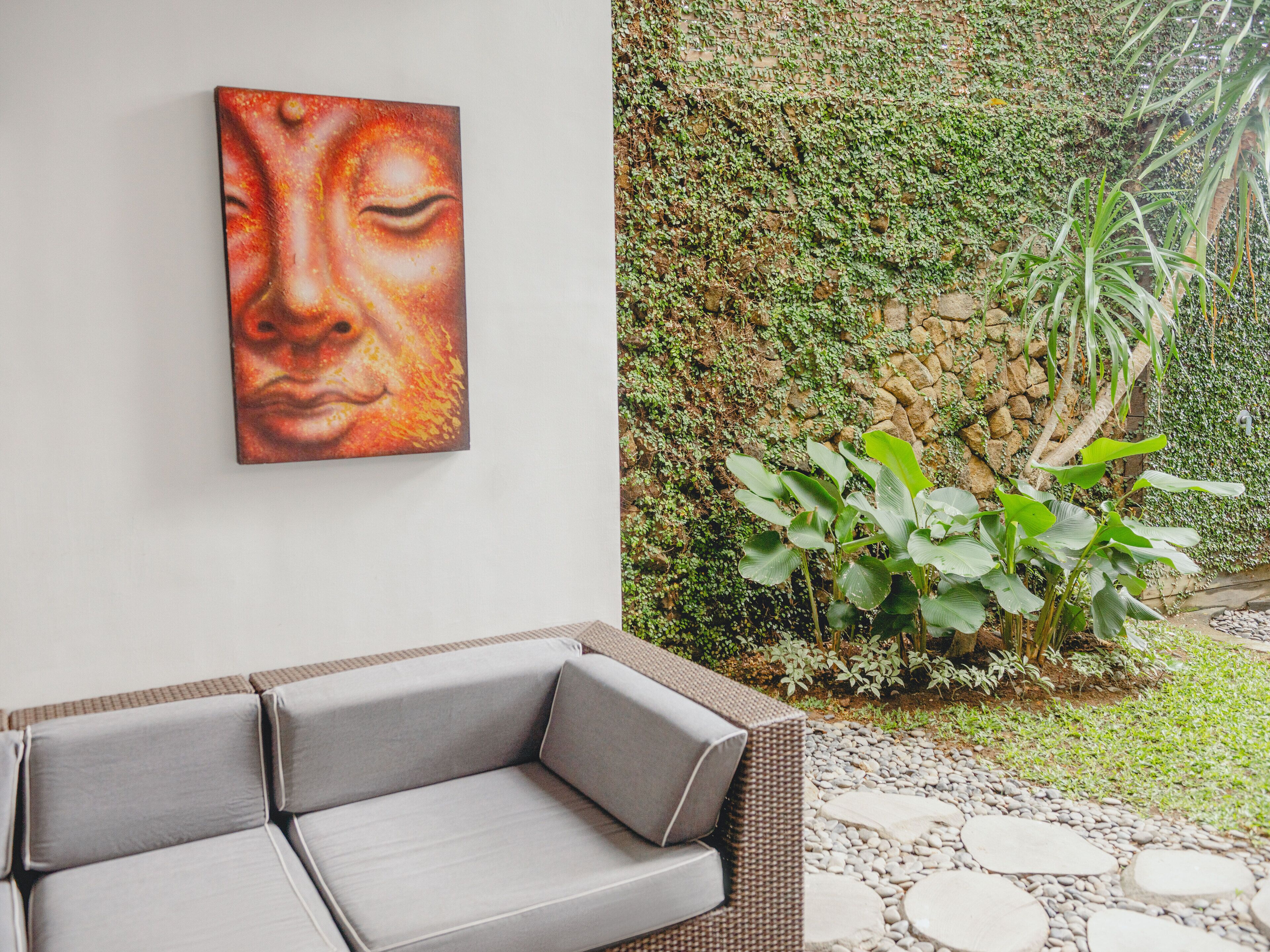 A modern outdoor seating area with a wicker sofa and a stone pathway.