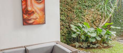 A modern outdoor seating area with a wicker sofa and a stone pathway.