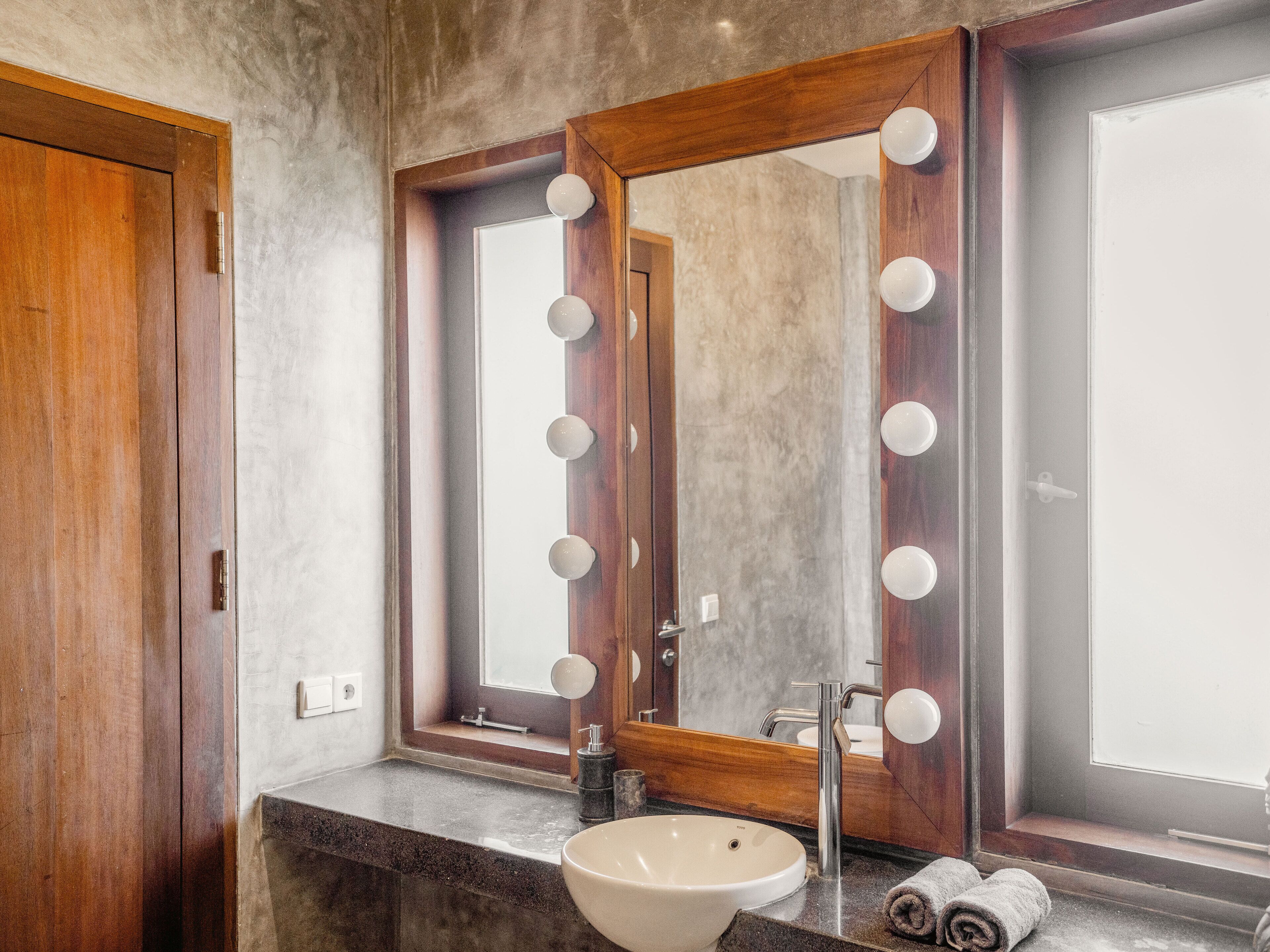 Een badkamer met een grote spiegel, wastafel, badkamermeubel en handdoekrek.
