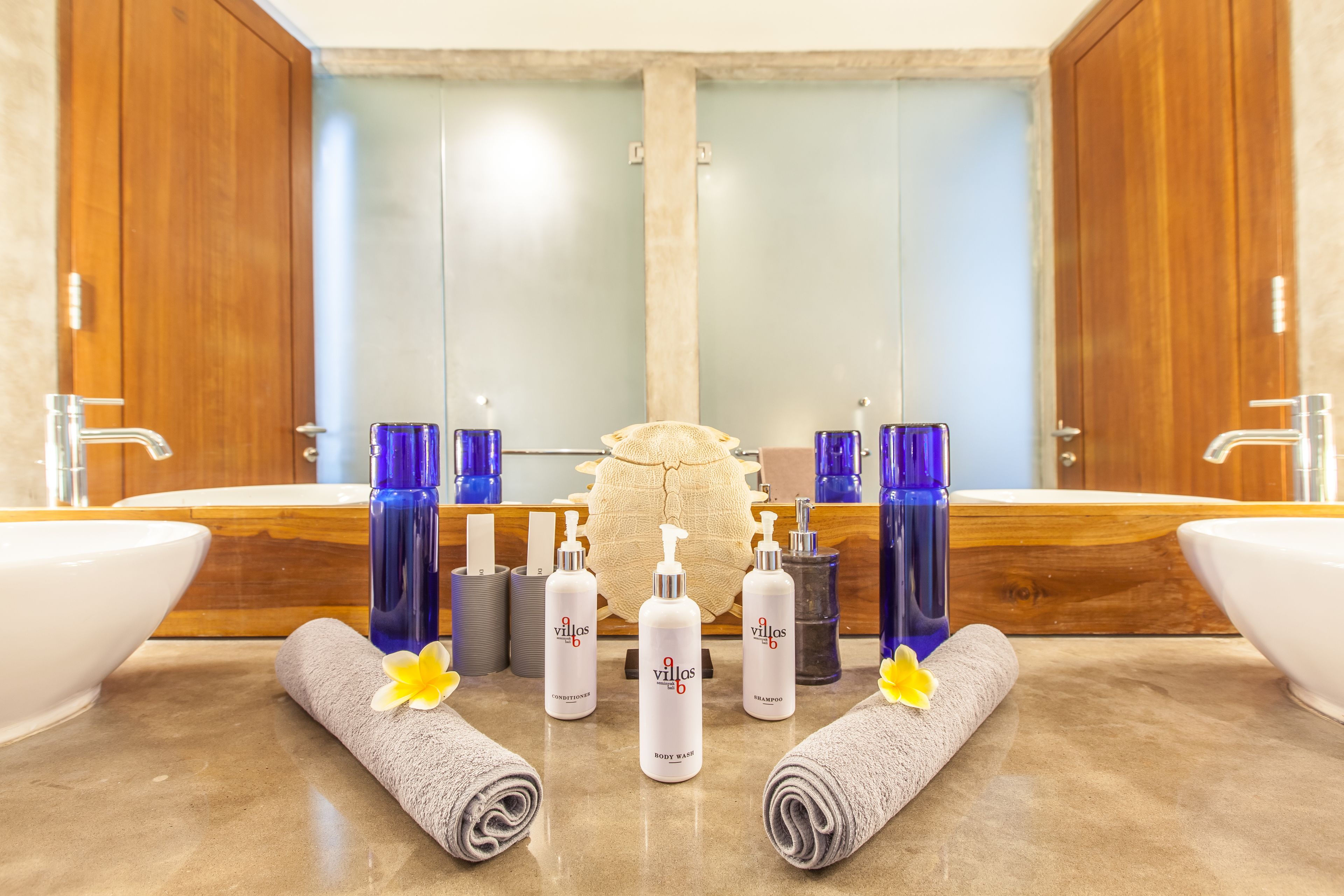 Une salle de bain avec deux lavabos, un miroir et divers produits de toilette disposés sur le comptoir.