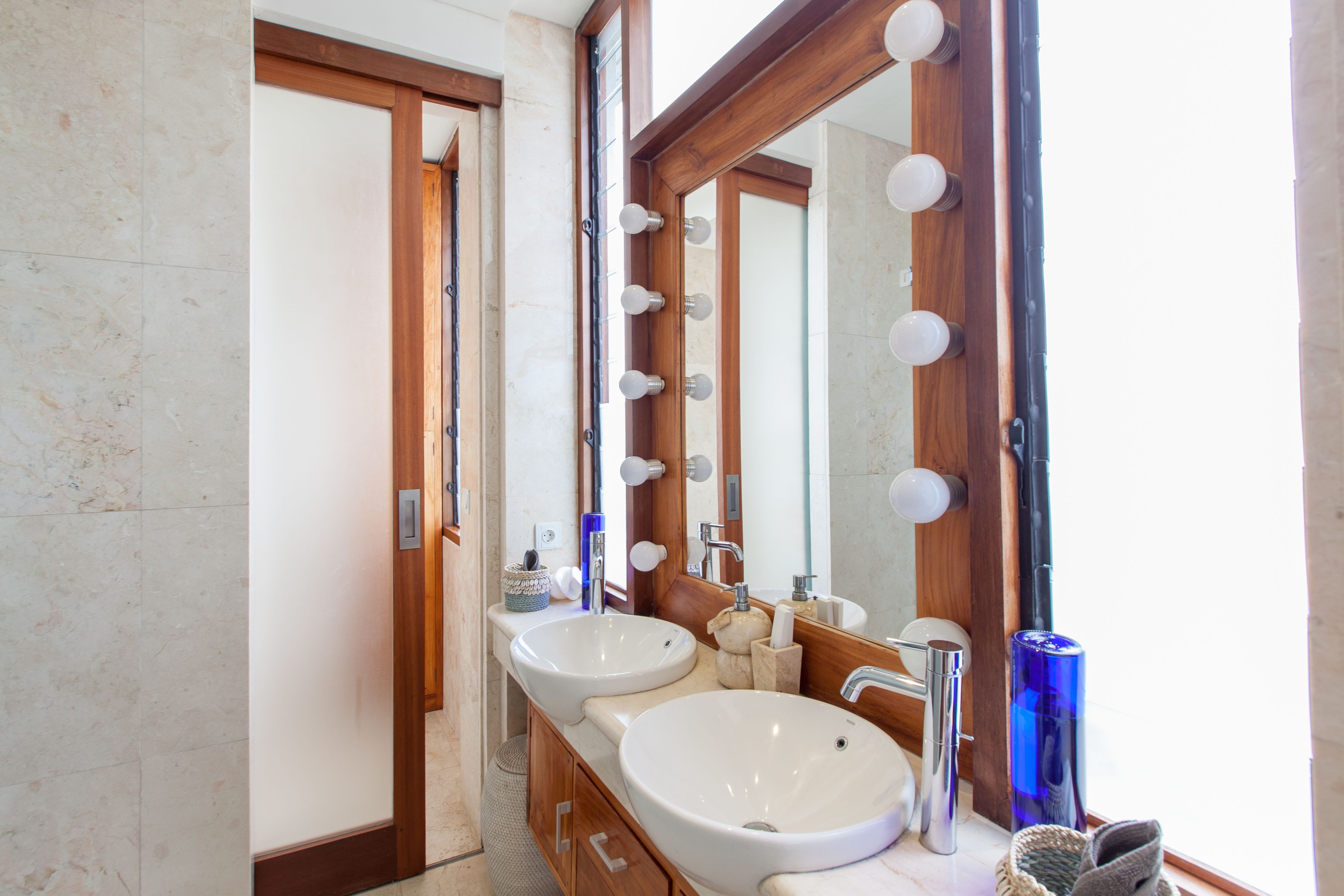 A bathroom with two sinks, a large mirror, and a vanity with a wooden frame.