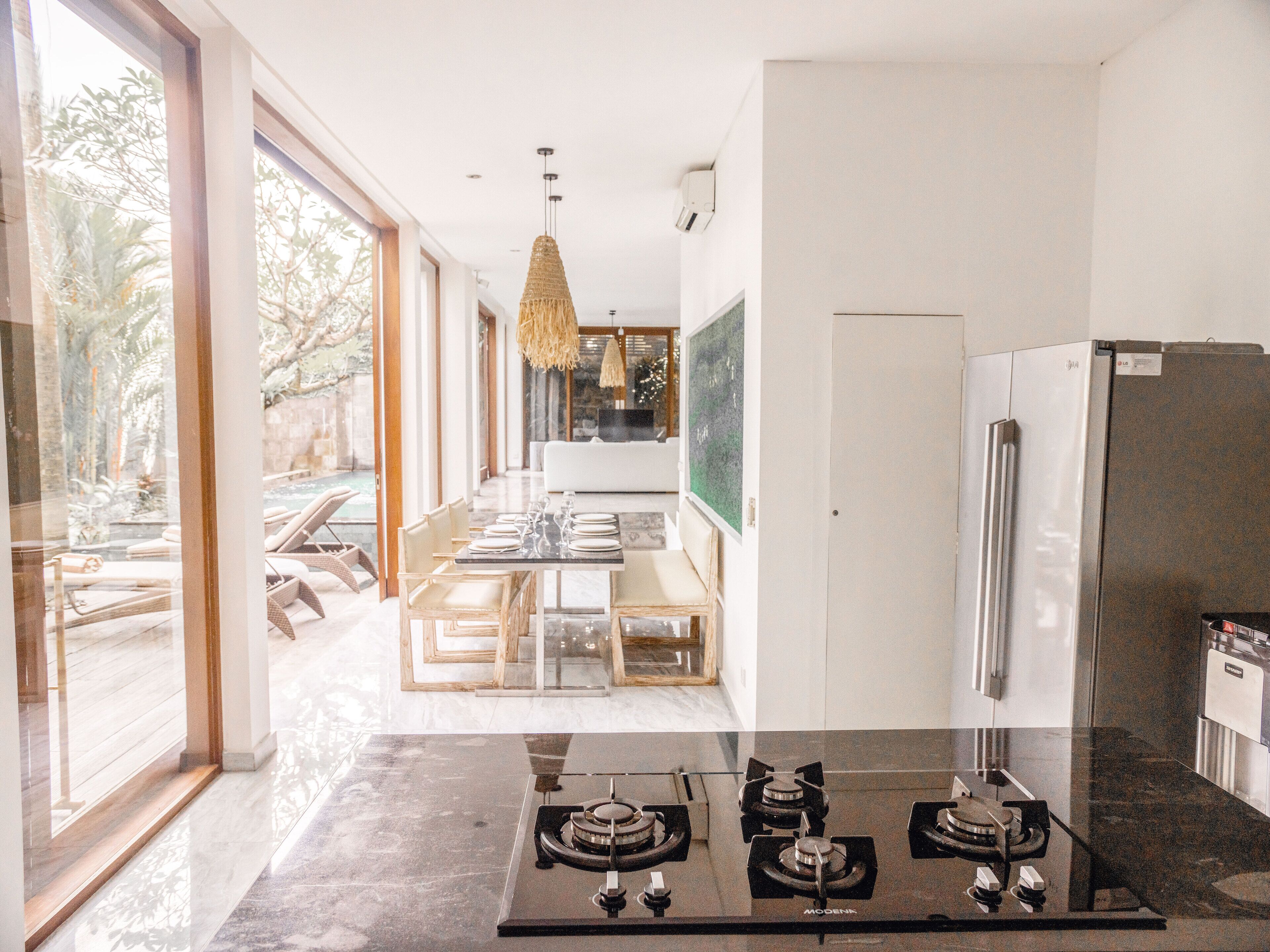 A modern kitchen with a gas stove, a refrigerator, and a dining area with a glass table and chairs.