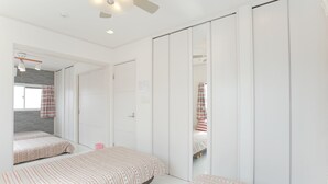 A bedroom with two beds, a wardrobe, and a mirror. - Hostel Tengachaya 238 (Osaka)