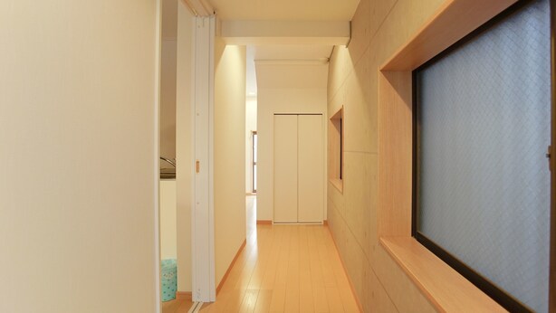 A narrow hallway with wooden flooring, white walls, and a door at the end. - Hostel Tengachaya 238 (Osaka)