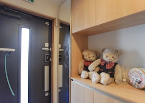 A room with a wooden shelf holding two teddy bears and a Disney Easter-themed plate.