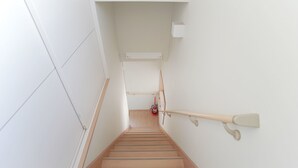 A staircase with wooden steps, white walls, and a handrail. - Hostel Tengachaya 238 (Osaka)