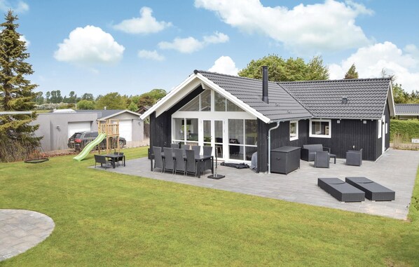 A modern house with a patio, outdoor seating, and a play area.