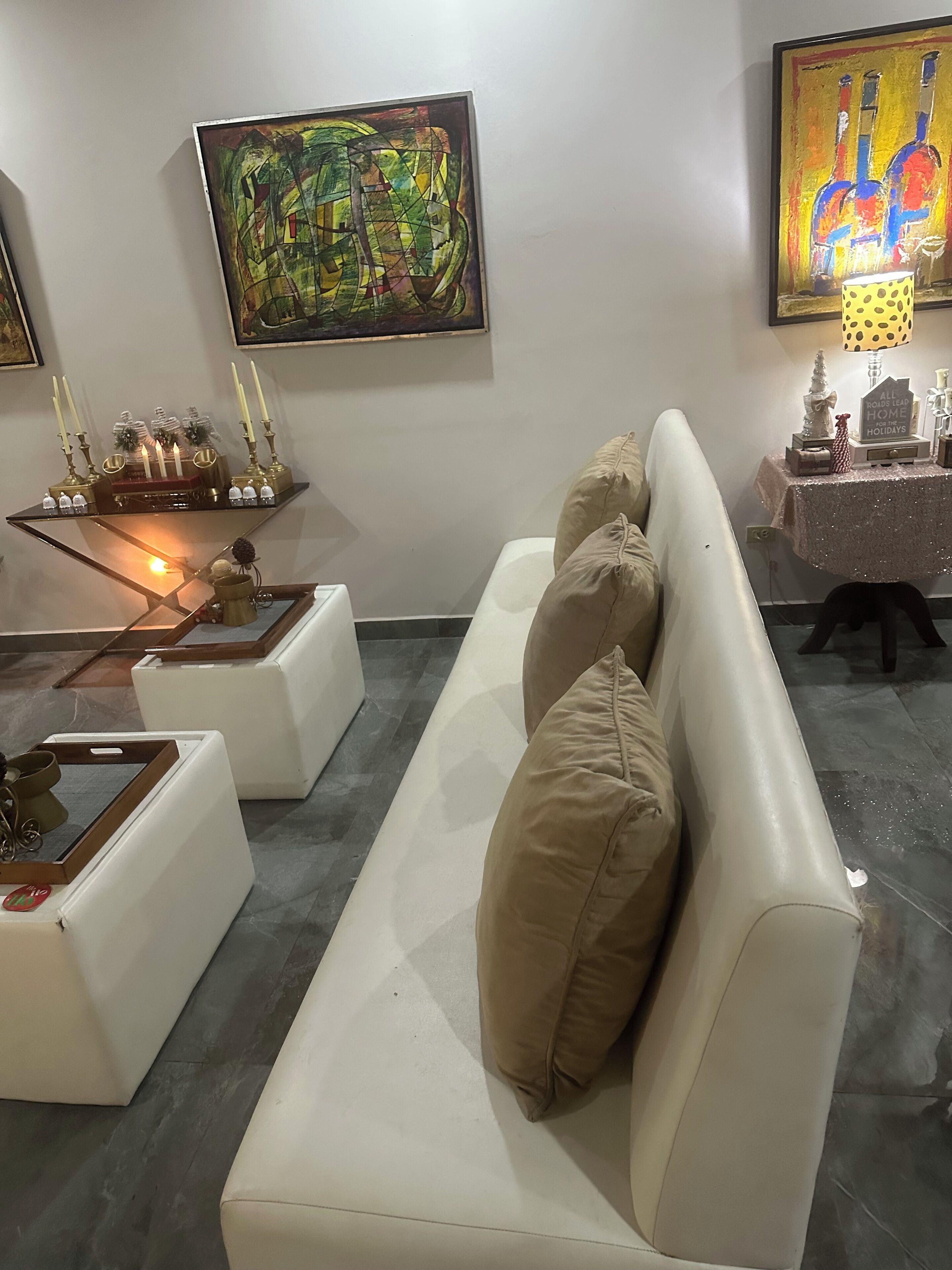 A modern living room with a white sofa, a glass coffee table, and a painting on the wall.