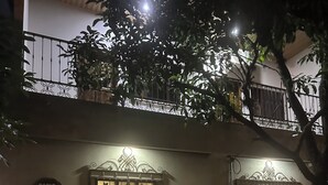 A building with a gated entrance, a sign reading 'Patio de Joan,' and potted plants around the entrance. - Patio De Joan (Comayagua)