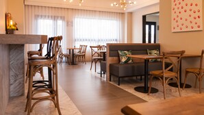 En modern hotellobby med trämöbler, en receptionsdisk i marmor och stora fönster med tunna, genomskinliga gardiner.