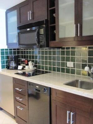 Kitchen features a microwave, coffee maker, and stainless steel sink with a faucet, along with a dishwasher and ample storage.