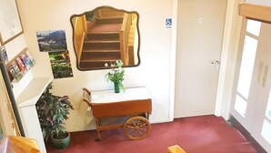 A staircase with a wooden handrail leading to a landing. A small cart with a plant is on the landing. - Geraldine Heritage Hotel (Geraldine)