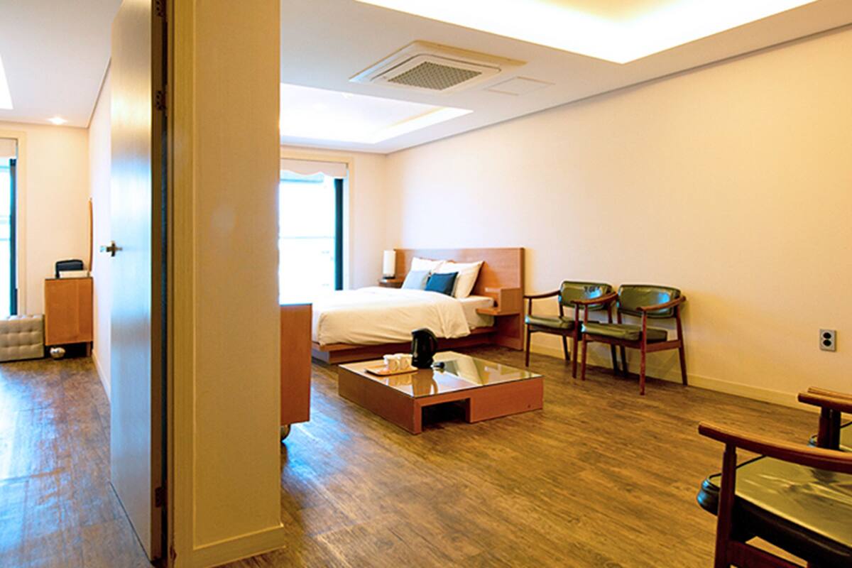 A hotel room with a bed, a coffee table, and a seating area with chairs.
