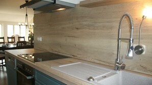 A kitchen with a wooden backsplash, stainless steel sink, and a modern stove. - 3) Holiday apartment 4-room, upper floor, 110m² - Landhaus Alte Schule near (Alt Bukow)