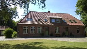 A two-story brick house with a tiled roof, multiple windows, and a paved driveway.