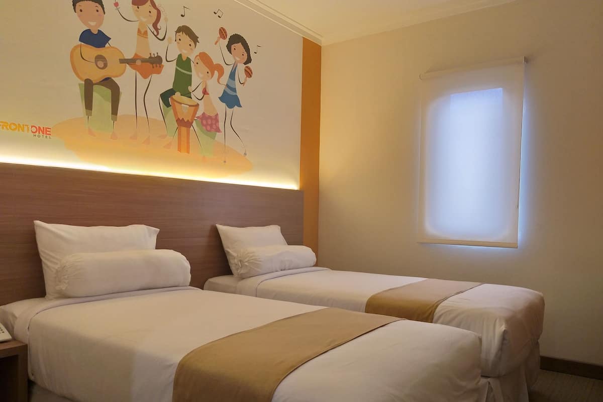 Habitación de hotel con dos camas, un mural en la pared y un ventanal.