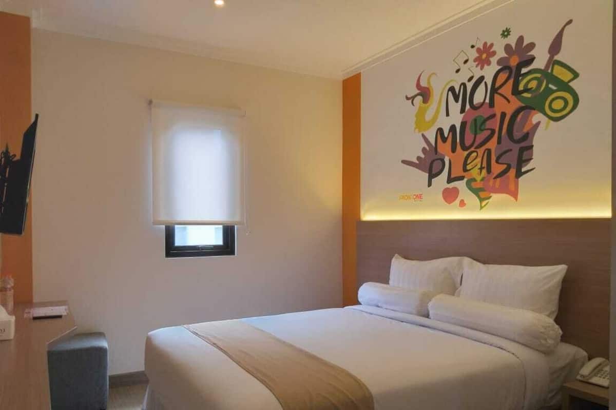 Una habitación de hotel con cama, mesita de noche y un adorno en la pared.