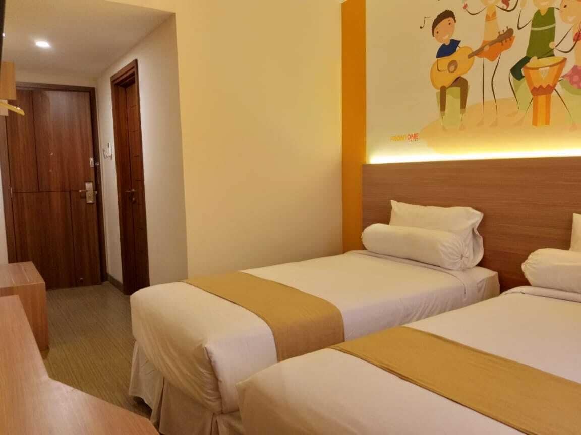 Habitación de hotel con dos camas, cabecero de madera y un mural de músicos en la pared.