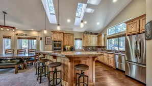 A spacious kitchen with a central island, wooden cabinets, stainless steel appliances, and a large window providing natural light.