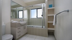 A modern bathroom with a glass shower enclosure, a sink, and a toilet. - 17 Sea Esplanade, Elliott Heads (ELLIOTT HEADS)